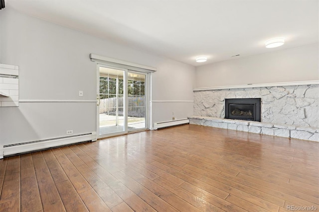 unfurnished living room featuring baseboard heating, a fireplace, hardwood / wood-style floors, and a baseboard radiator