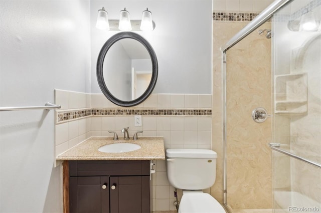 full bathroom featuring vanity, toilet, tile walls, and a shower stall