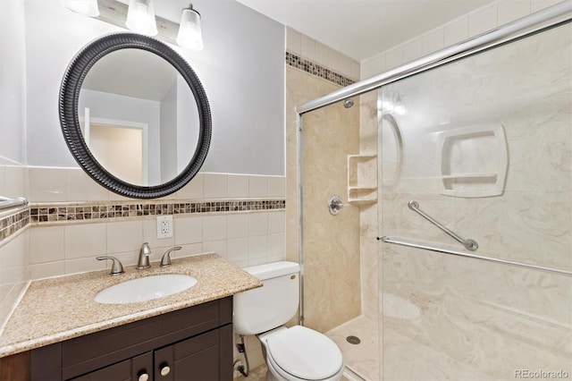 full bath with toilet, a stall shower, tile walls, and vanity