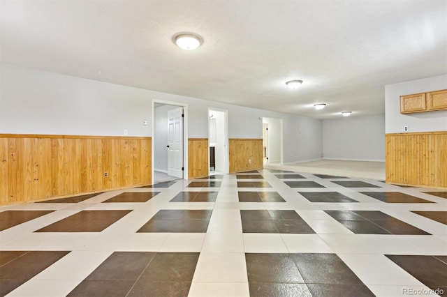 below grade area featuring tile patterned floors, wainscoting, and wood walls