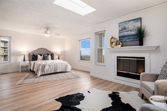 44 S Holman Way, Golden, CO 80401 - bedroom featuring a textured ceiling, a skylight, wood finished floors, a glass covered fireplace, and baseboards