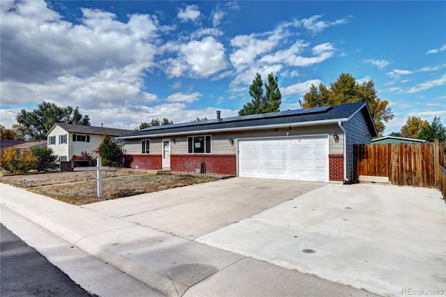 ranch-style home featuring a garage and solar panels