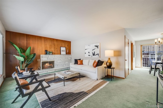 living room featuring carpet floors, a notable chandelier, wooden walls, and a fireplace