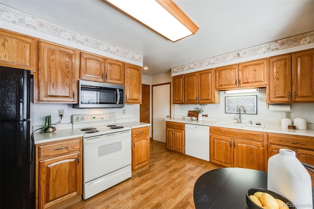 kitchen with sink, white appliances, and light wood-type flooring