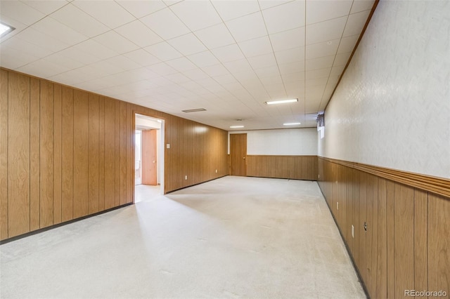 basement featuring light colored carpet and wood walls