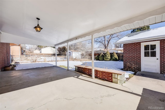 snow covered patio featuring a shed