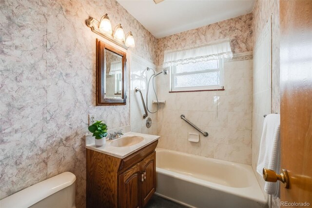 full bathroom featuring vanity, tiled shower / bath, and toilet