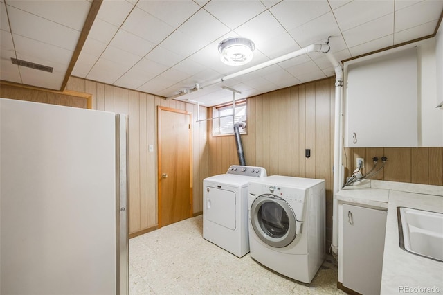 laundry area featuring sink, washer and clothes dryer, cabinets, and wooden walls