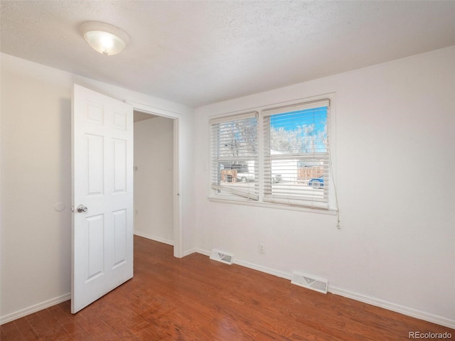 unfurnished bedroom with wood-type flooring and a textured ceiling