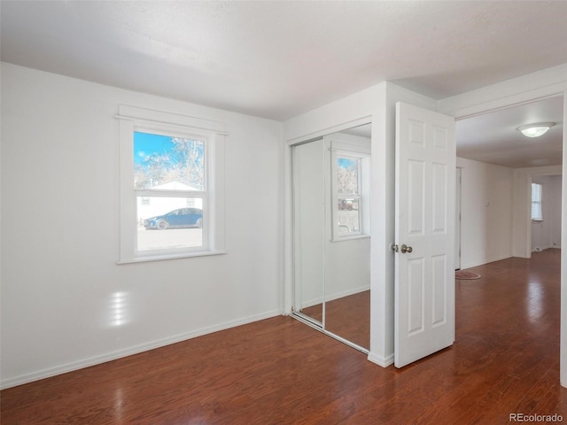 unfurnished bedroom with a closet and dark wood-type flooring