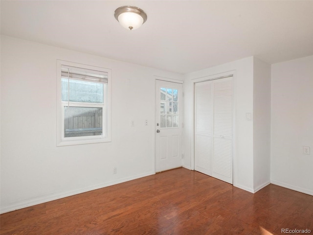 unfurnished bedroom with multiple windows, dark hardwood / wood-style floors, and a closet