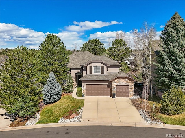 french provincial home with a garage, concrete driveway, a shingled roof, stone siding, and stucco siding
