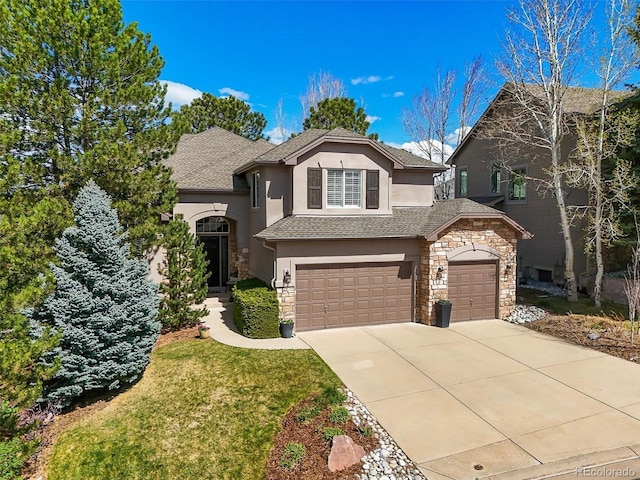 traditional-style home with stucco siding, an attached garage, driveway, and stone siding