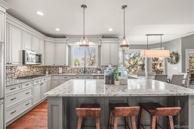 kitchen featuring a kitchen island, a breakfast bar, tasteful backsplash, a sink, and stainless steel appliances