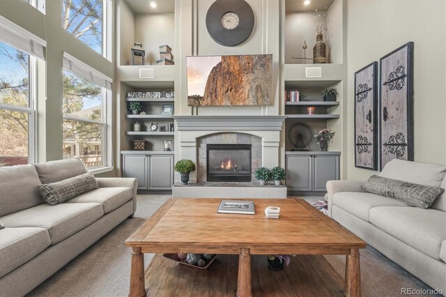 living room with a fireplace, recessed lighting, built in features, and a towering ceiling