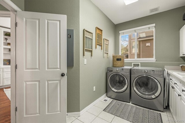 clothes washing area with baseboards, cabinet space, independent washer and dryer, and a textured wall