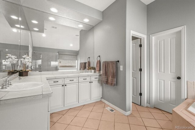 bathroom featuring double vanity, visible vents, tile patterned flooring, a tile shower, and a sink