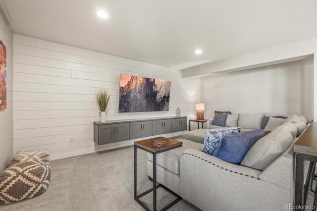 living area with wooden walls, recessed lighting, and light colored carpet