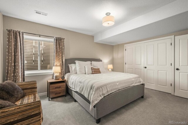 carpeted bedroom with visible vents and a closet