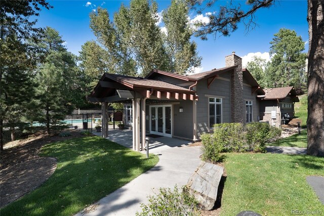 exterior space featuring a patio, a yard, french doors, and a chimney