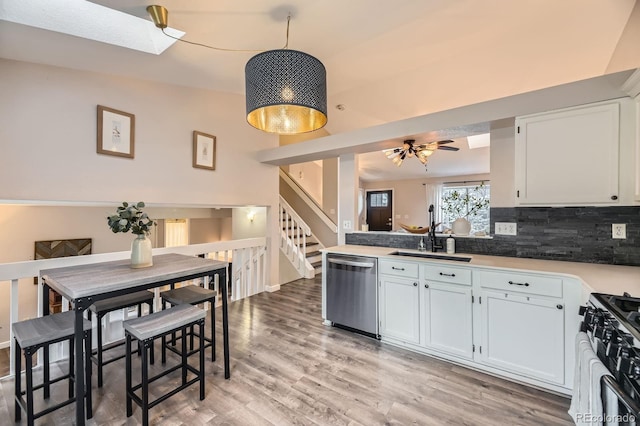 12476 W Prentice Pl, Littleton, CO 80127 - kitchen with stainless steel dishwasher, range with gas stovetop, decorative backsplash, light wood finished floors, and white cabinets