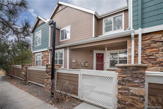 townhome / multi-family property featuring stone siding and a porch