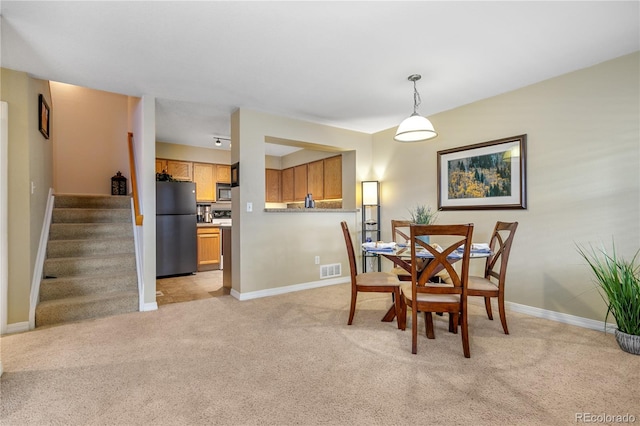 dining area with visible vents, baseboards, light colored carpet, and stairway