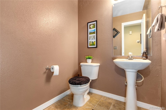 half bathroom featuring tile patterned flooring, toilet, and baseboards