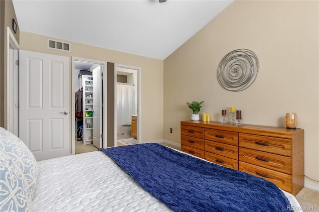 bedroom with visible vents, ensuite bath, baseboards, lofted ceiling, and a spacious closet