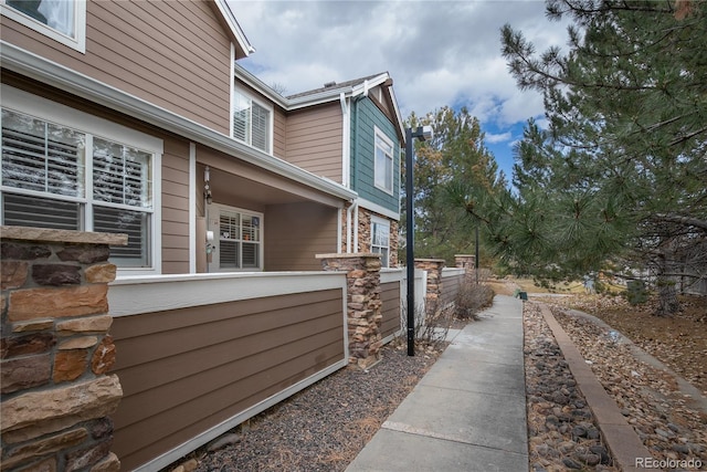 view of home's exterior featuring stone siding and fence