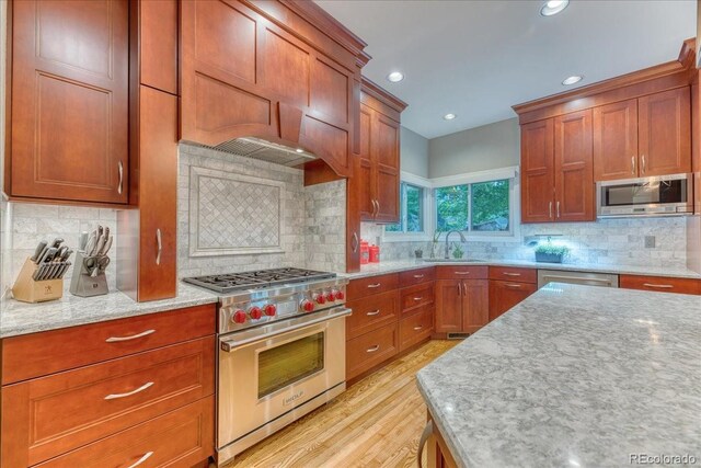 16642 W Archer Ave, Golden, CO 80401 - kitchen with stainless steel appliances, light stone countertops, decorative backsplash, light wood-style floors, and brown cabinetry