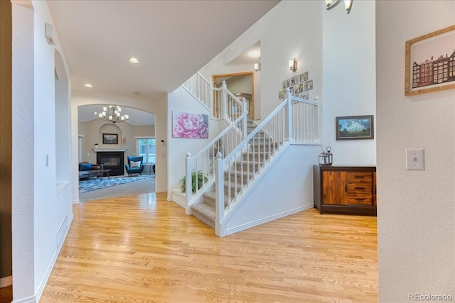 16642 W Archer Ave, Golden, CO 80401 - stairs with wood finished floors, arched walkways, a glass covered fireplace, a chandelier, and recessed lighting