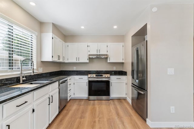 9015 W Tanforan Dr, Littleton, CO 80123 - kitchen featuring stainless steel appliances, under cabinet range hood, light wood-style floors, dark stone countertops, and white cabinetry
