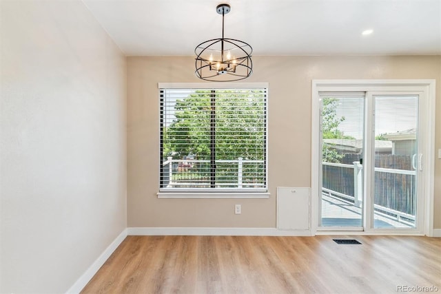 9015 W Tanforan Dr, Littleton, CO 80123 - unfurnished dining area featuring wood finished floors, a chandelier, and plenty of natural light
