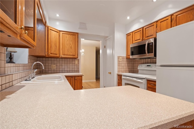9115 W 5th Ave, Lakewood, CO 80226 - kitchen with white appliances, a sink, light countertops, backsplash, and brown cabinetry