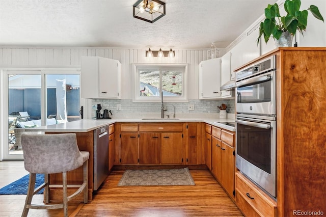 5384 Olde Stage Rd, Boulder, CO 80302 - kitchen with a peninsula, light wood-type flooring, a textured ceiling, a sink, and appliances with stainless steel finishes