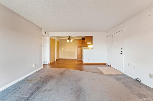 spare room with light carpet, visible vents, a textured ceiling, and a ceiling fan