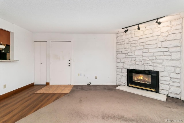 unfurnished living room featuring baseboards, a textured ceiling, wood finished floors, and a fireplace