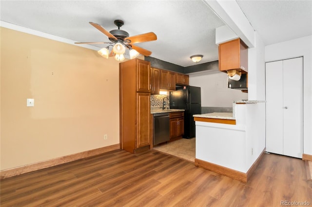 kitchen featuring freestanding refrigerator, ceiling fan, light countertops, light wood-style floors, and dishwasher