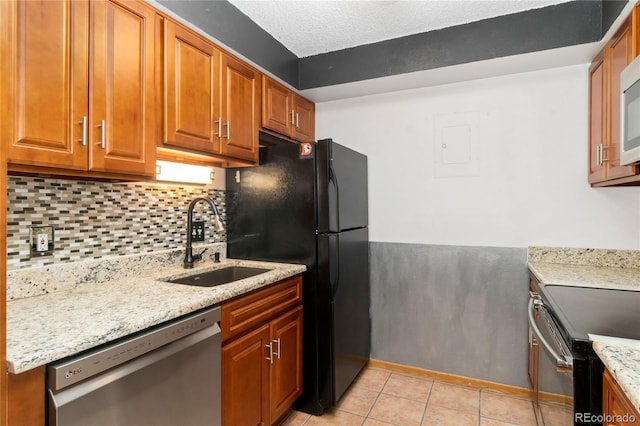 kitchen featuring a sink, tasteful backsplash, stainless steel appliances, light tile patterned floors, and light stone countertops