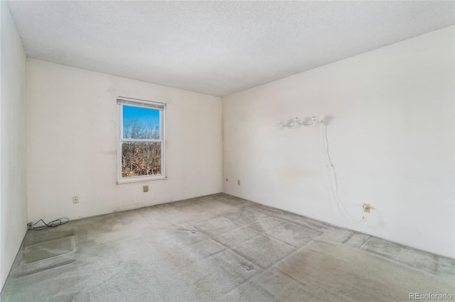 unfurnished room featuring carpet and a textured ceiling