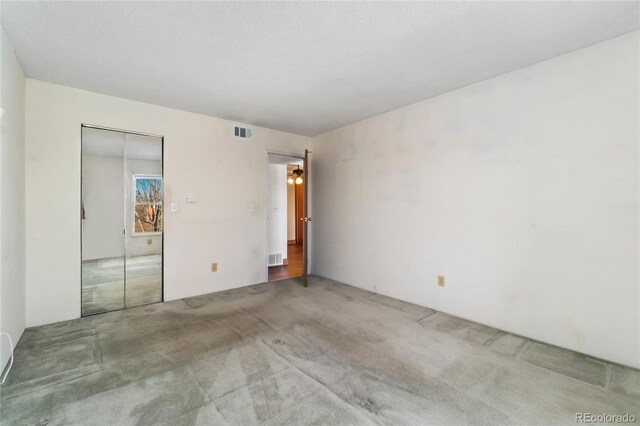 unfurnished bedroom featuring carpet, visible vents, and a closet