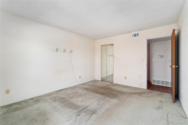 interior space featuring a closet, visible vents, carpet floors, and a textured ceiling