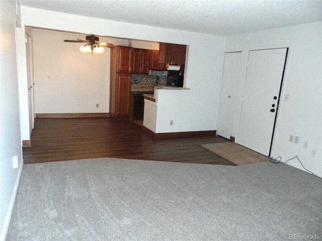 unfurnished living room with a ceiling fan, baseboards, and carpet