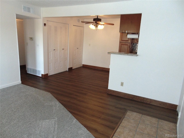 unfurnished living room featuring wood finished floors, visible vents, a ceiling fan, and baseboards