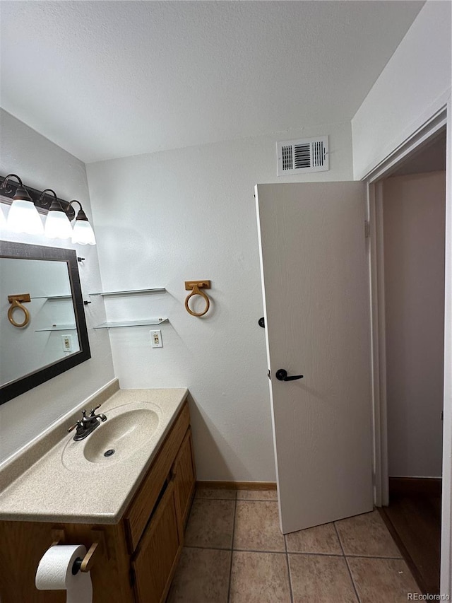 bathroom with vanity, baseboards, tile patterned flooring, a textured ceiling, and visible vents