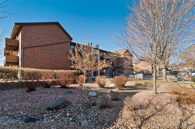 view of property exterior with fence and brick siding