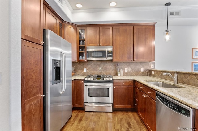 1776 Race St Unit 109, Denver, CO 80206 - kitchen featuring appliances with stainless steel finishes, light wood-type flooring, light stone countertops, glass insert cabinets, and brown cabinetry