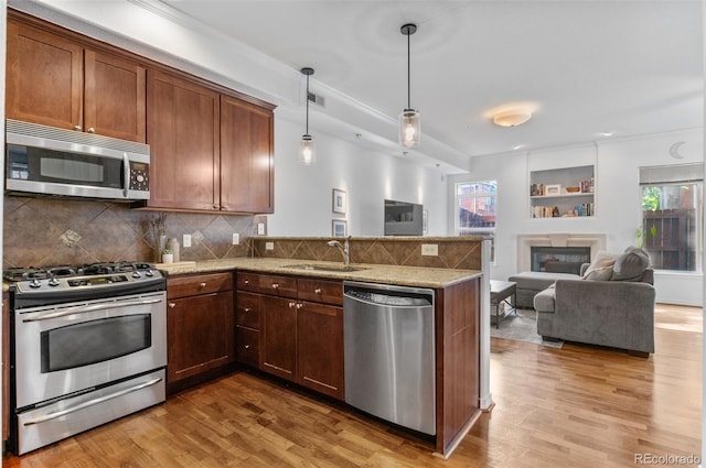 1776 Race St Unit 109, Denver, CO 80206 - kitchen featuring appliances with stainless steel finishes, open floor plan, a glass covered fireplace, light wood-style floors, and ornamental molding