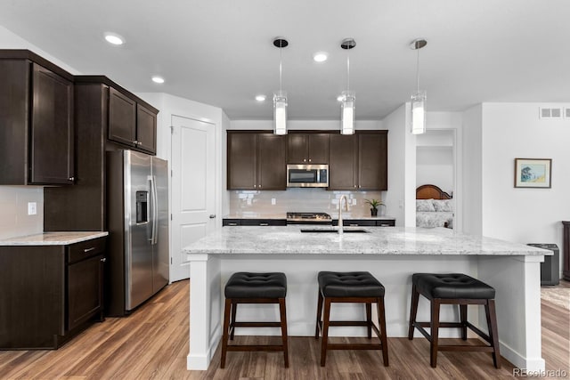 15802 Xanthia Way, Thornton, CO 80602 - kitchen featuring appliances with stainless steel finishes, light wood-style flooring, dark brown cabinets, a breakfast bar area, and recessed lighting